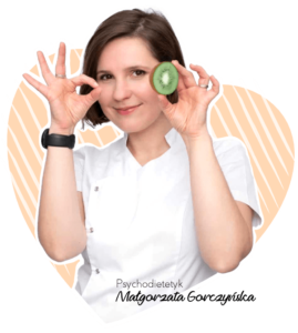 Kobieta w białej koszuli trzyma kiwi w dłoni, uśmiechając się do obiektywu.
